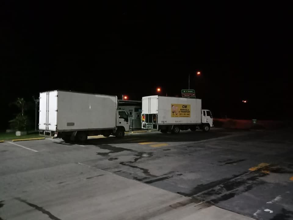 Two White Trucks Are Parked in a Parking Lot at Night — CM Removals & Transport In Cooroy, QLD
