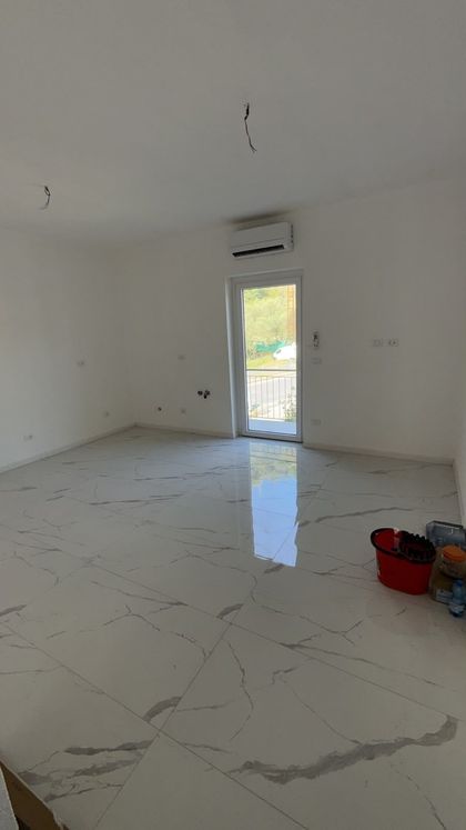 Stretto corridoio esterno lastricato in mattoni accanto a un condominio, con una sedia in fondo e uno stendibiancheria.