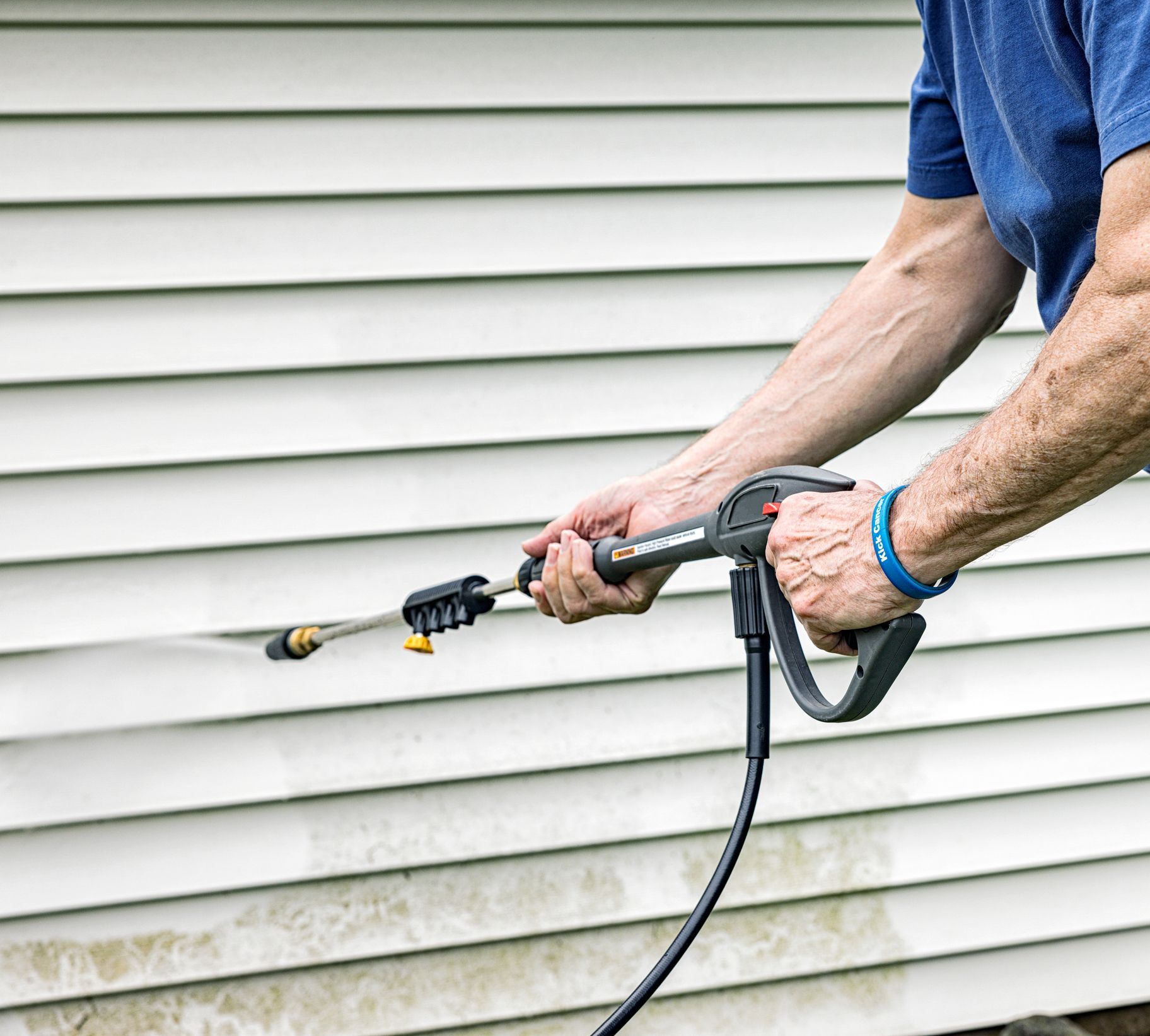 Person pressure washing house siding.