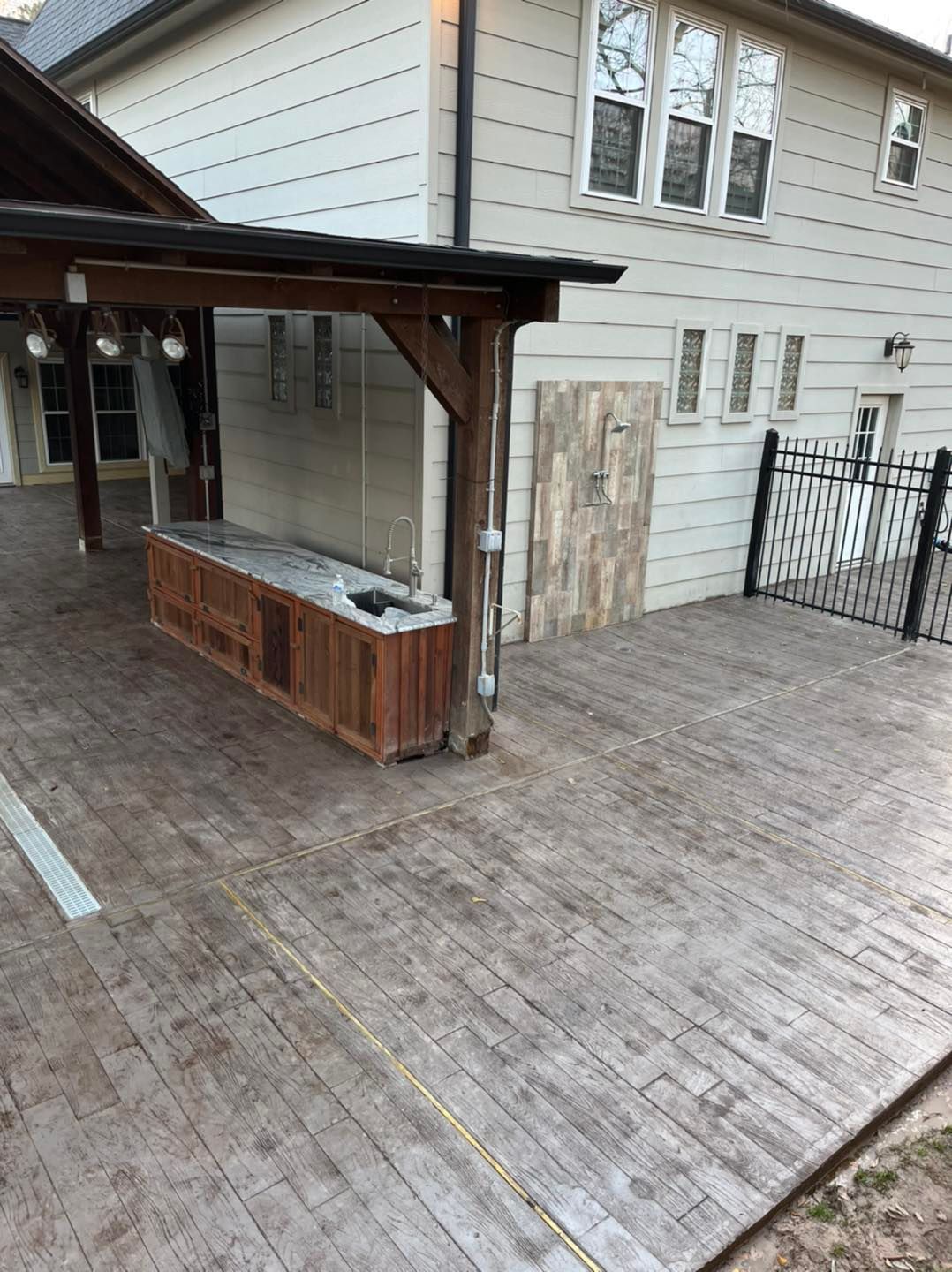 Wooden outdoor bar structure on a large deck, attached to a two-story house.