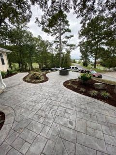 Grey stone patio with landscaped beds and trees.