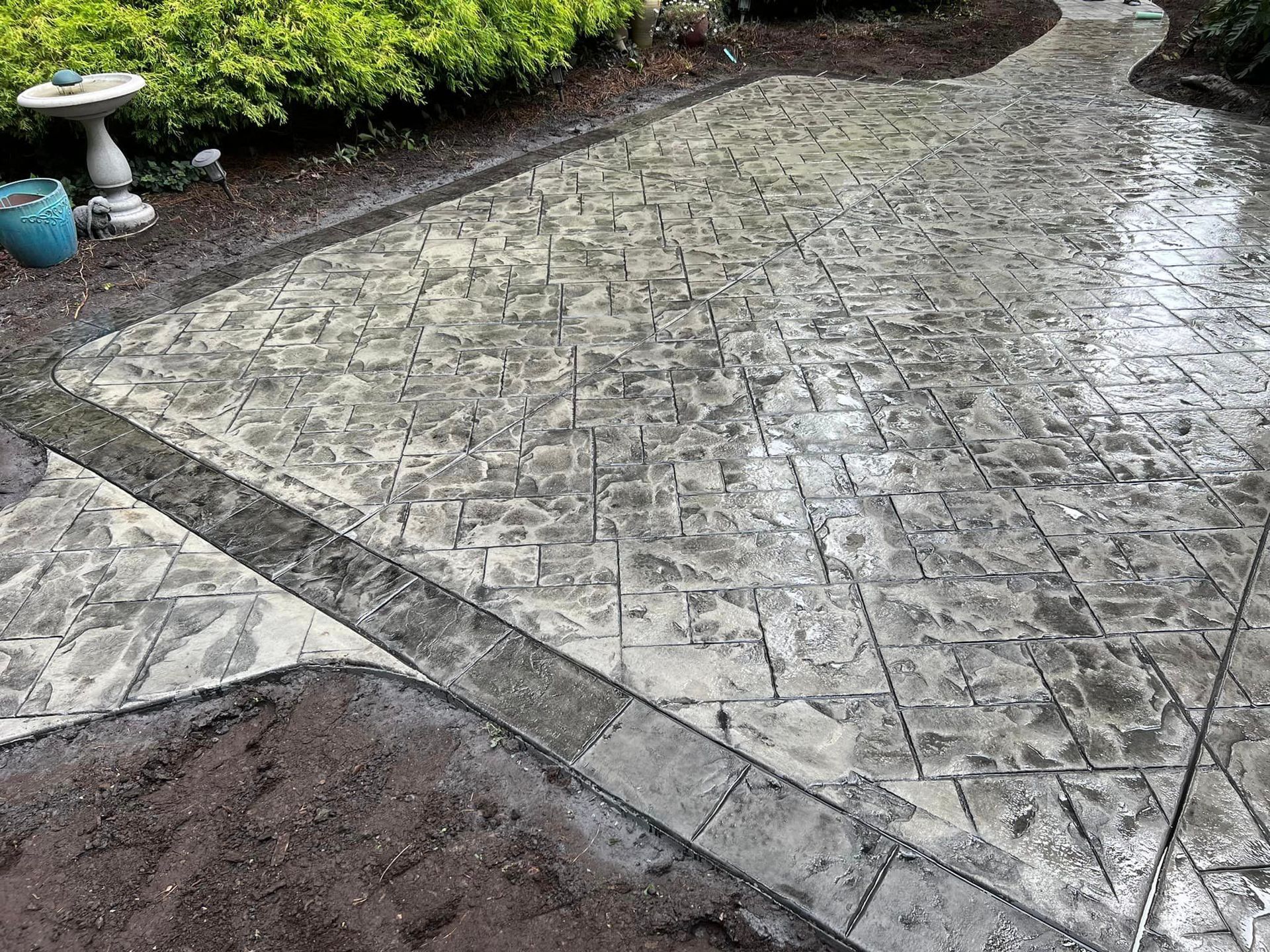 Stamped concrete patio with borders, flower bed in a garden setting.