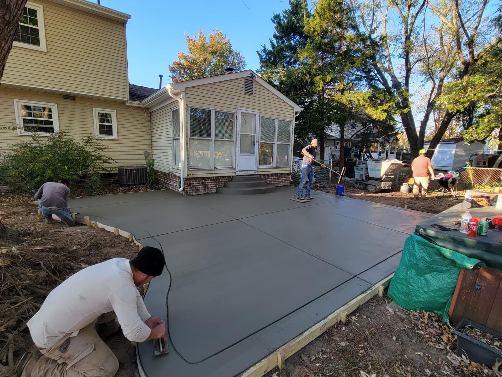 Construction workers pouring concrete patio in backyard.