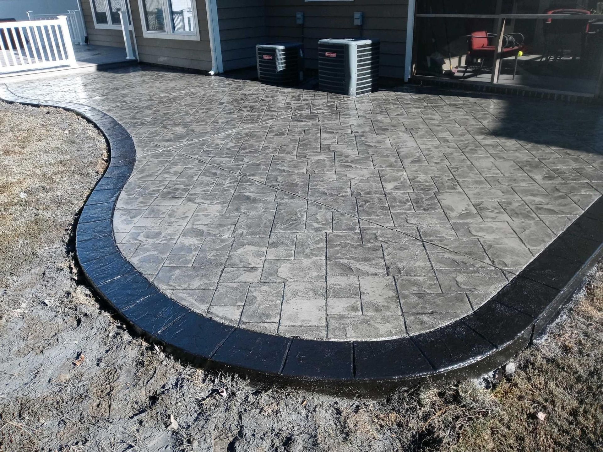 Stamped concrete patio with dark border, next to a house.