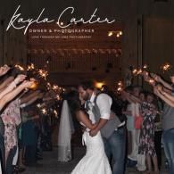 Bride and groom kissing under a sparkler arch at a dimly lit wedding reception