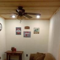 Living room with wood ceiling fan, wall art, and a small table by a beige chair.