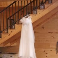 White wedding dress hanging on a staircase railing in a wooden interior