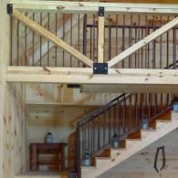 Loft view of a wooden staircase with railings and a small table beneath it