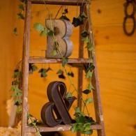 Decorative wooden ladder with vine garland and large letter B and ampersand on warm yellow wall