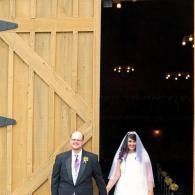 Bride and groom standing in a church doorway, the bride in a white veil and the groom in a dark suit.