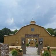 Rustic wooden barn entrance with white trim and flower planters under a cloudy sky