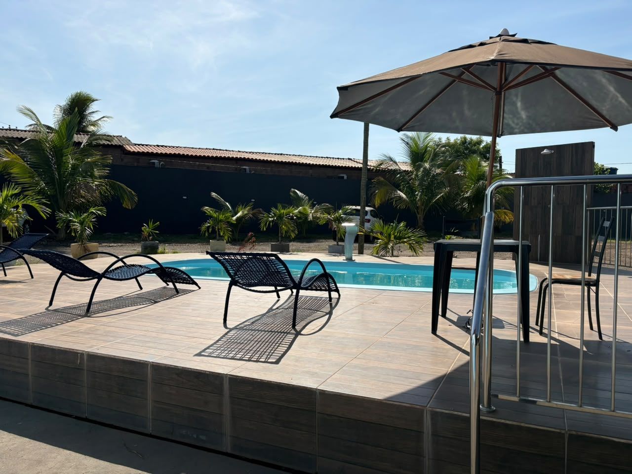 Espreguiçadeiras e guarda-sóis à beira da piscina em um resort ensolarado.