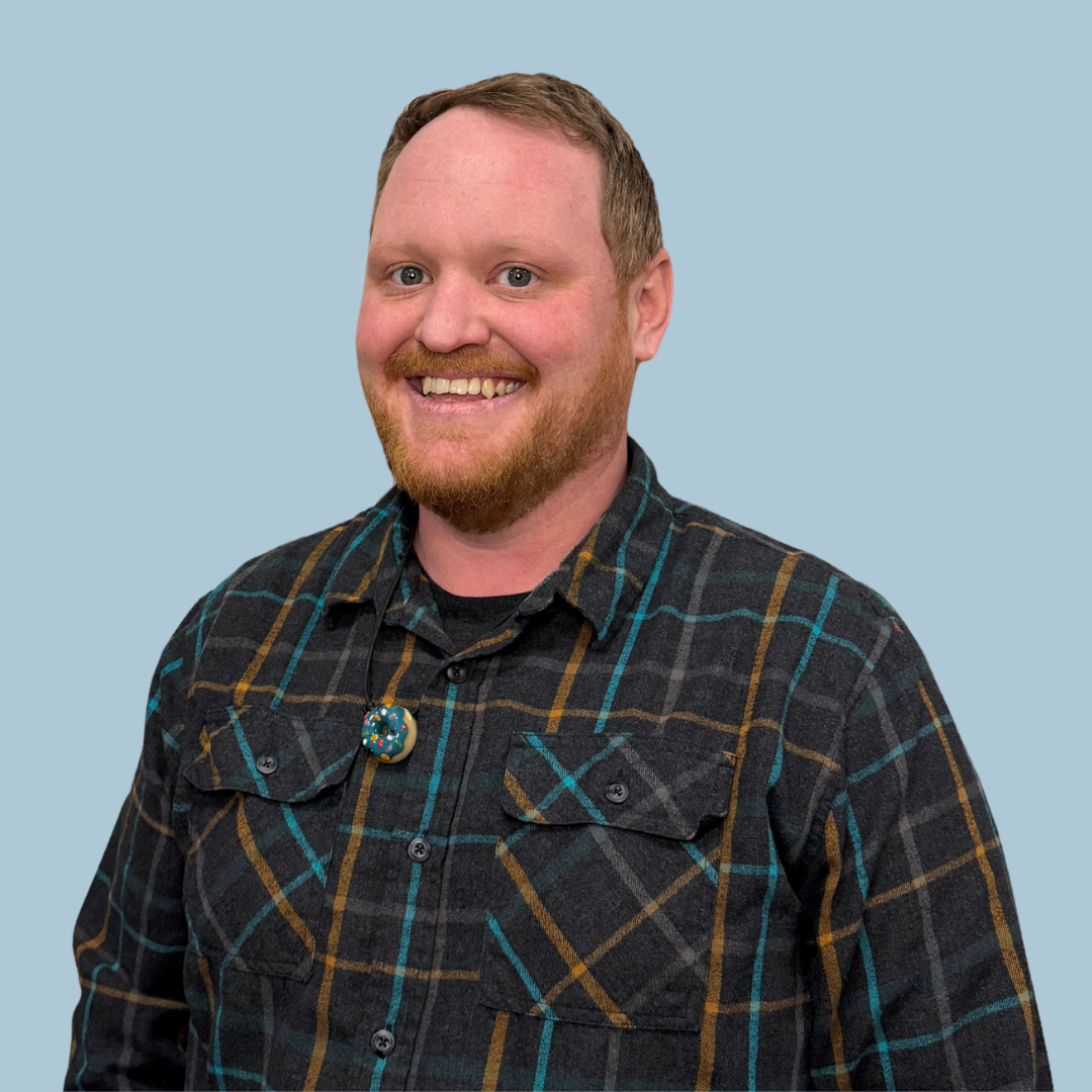 a man in a plaid shirt is sitting in a chair in front of a neon sign .