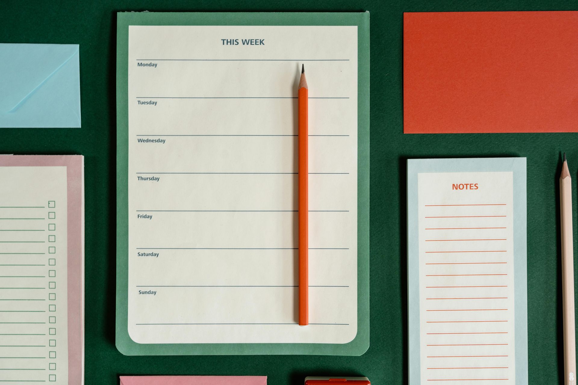 Green desk organizer with weekly planner and stationery items.