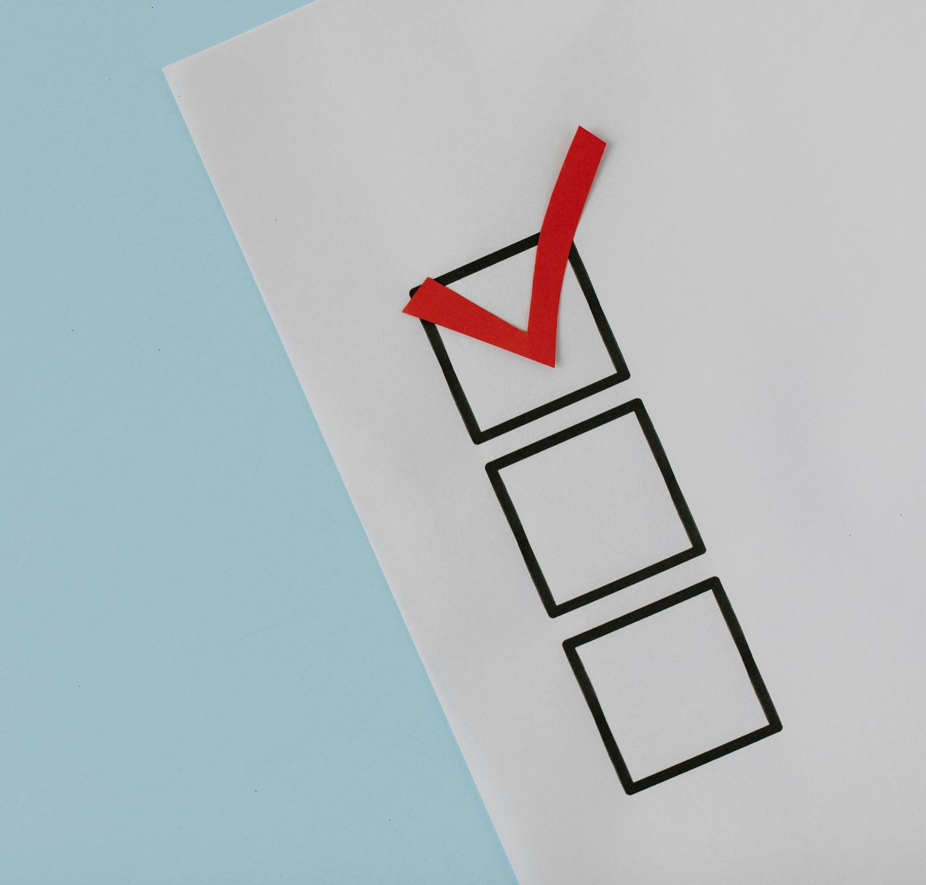 Red checkmark inside a black-lined square on a white paper with two empty squares; set on a blue background.