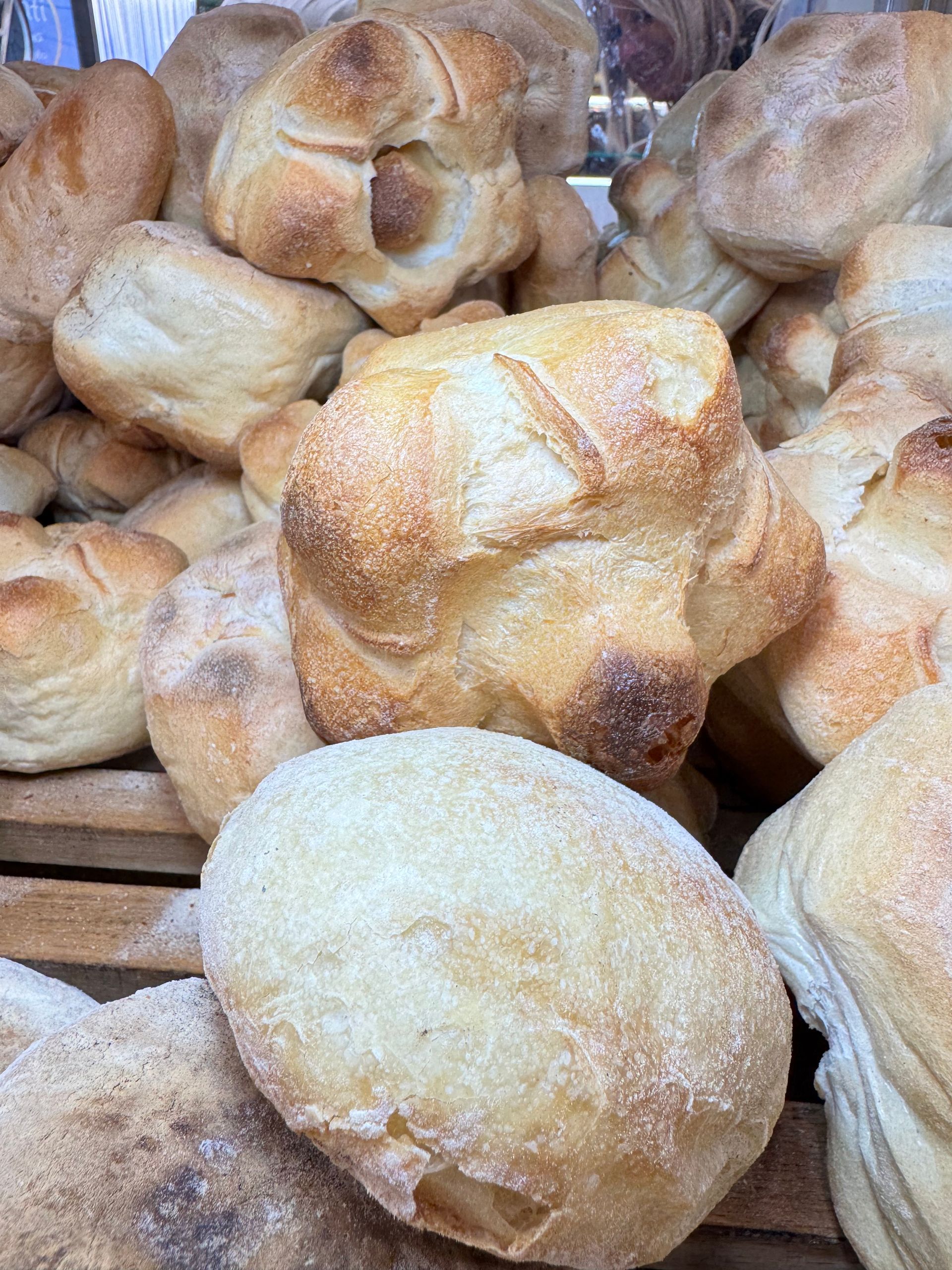 Assortimento di panini appena sfornati su un vassoio, dorati e cosparsi di farina