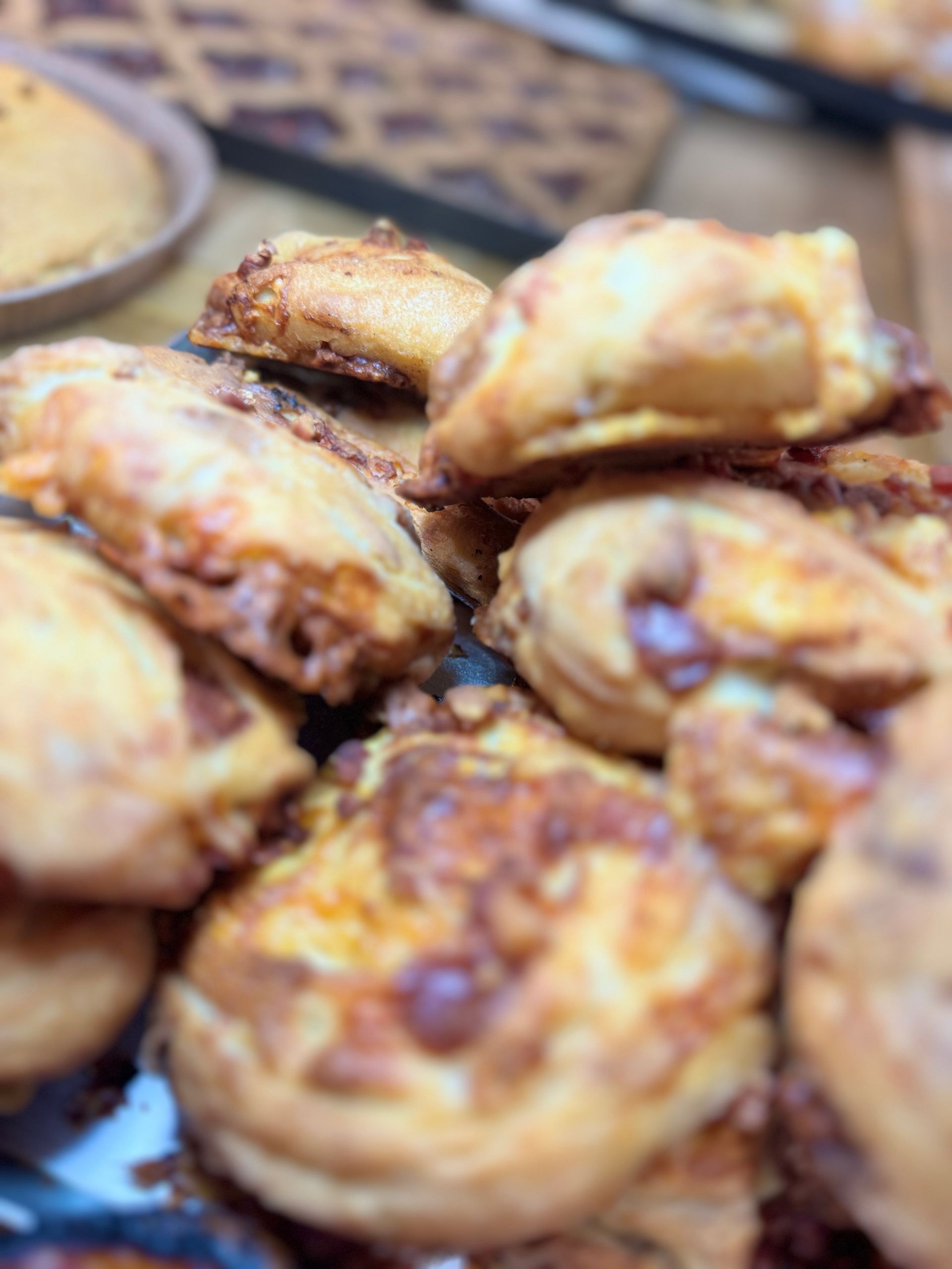 Vassoio di pasticcini dorati con una crosta friabile, impilati vicini su una superficie decorata.