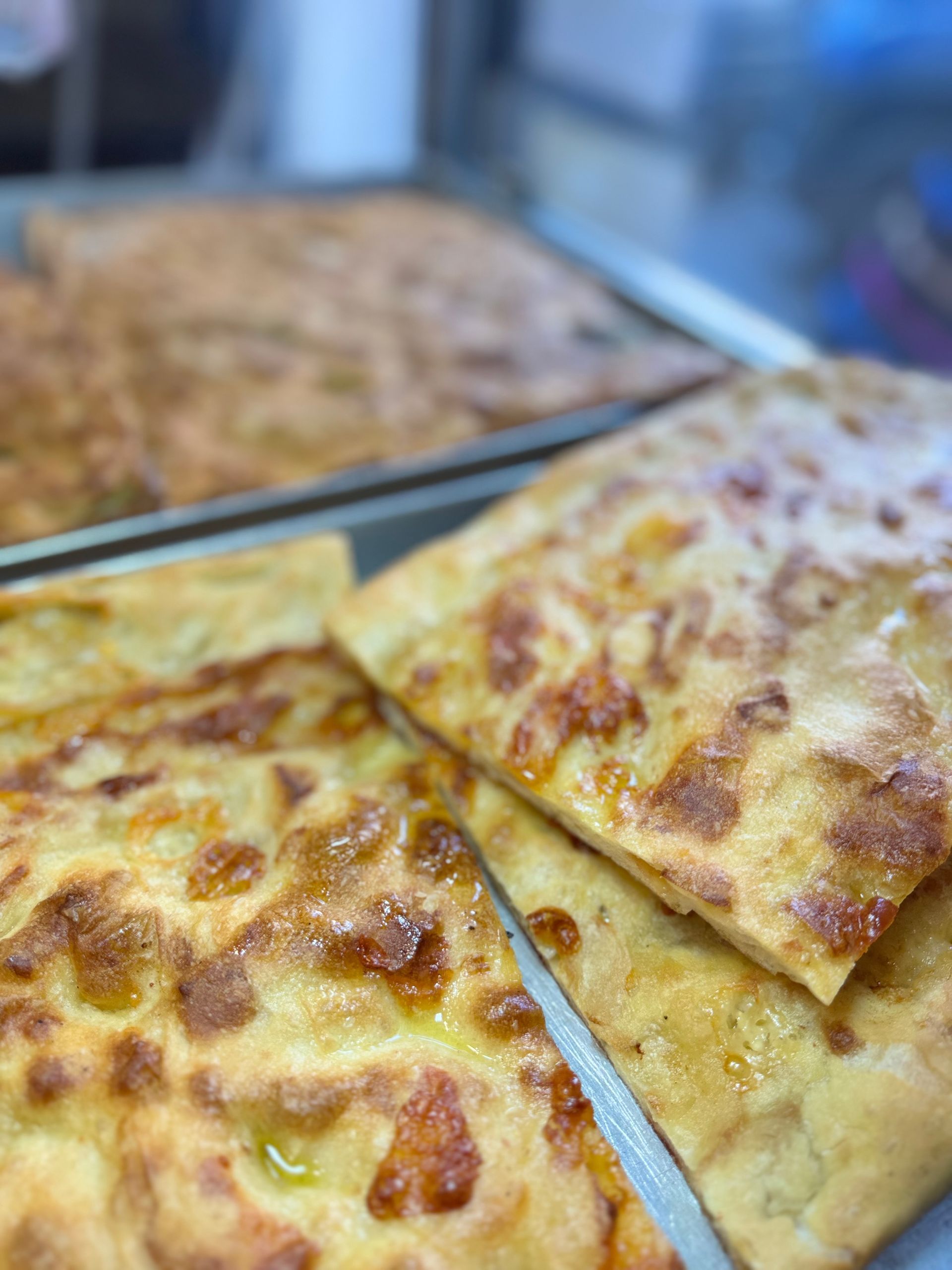 Vassoio di fette di focaccia cotte al forno e dorate con formaggio fuso, tagliate a triangoli su un bancone