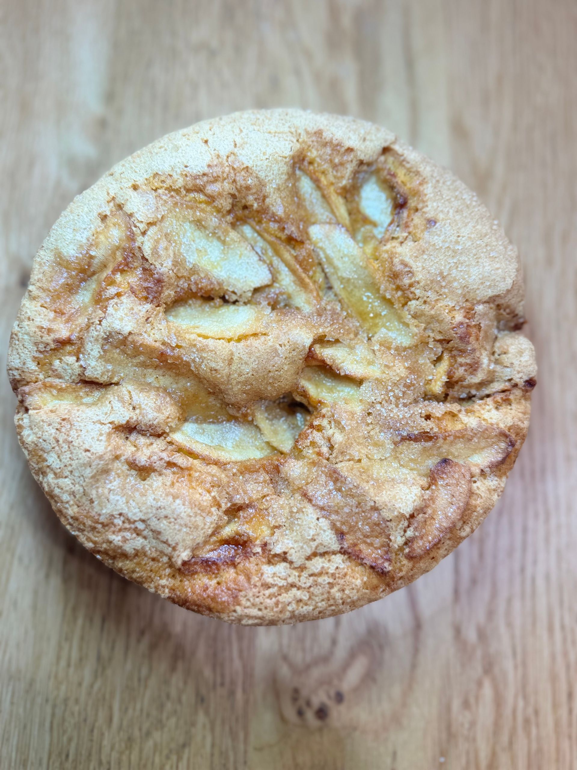 Torta rotonda di mele cosparsa di zucchero su una superficie di legno