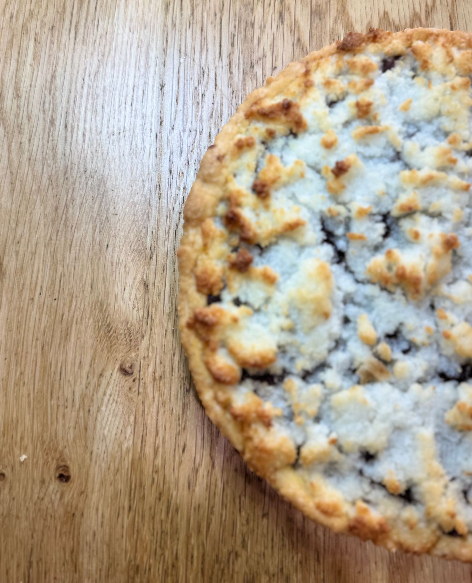Focaccia rotonda ricoperta di formaggio su un tagliere di legno.