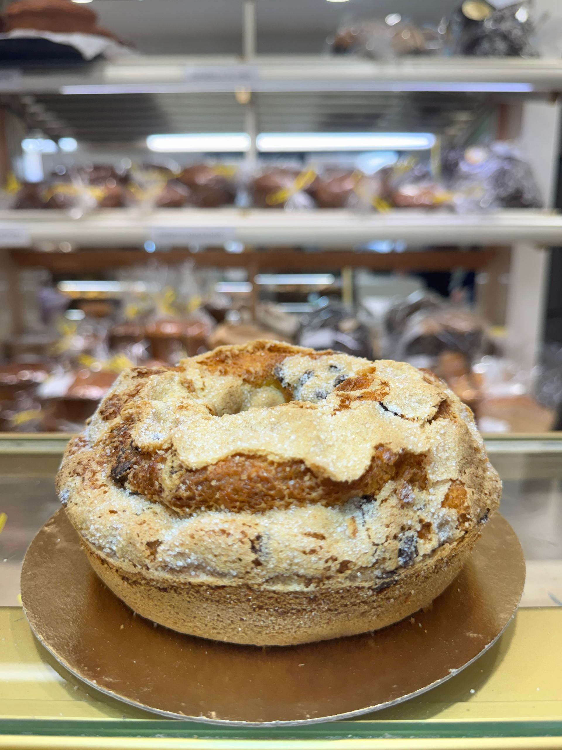 Pagnotta rotonda di pane artigianale su base di cartone in una vetrina da panetteria.