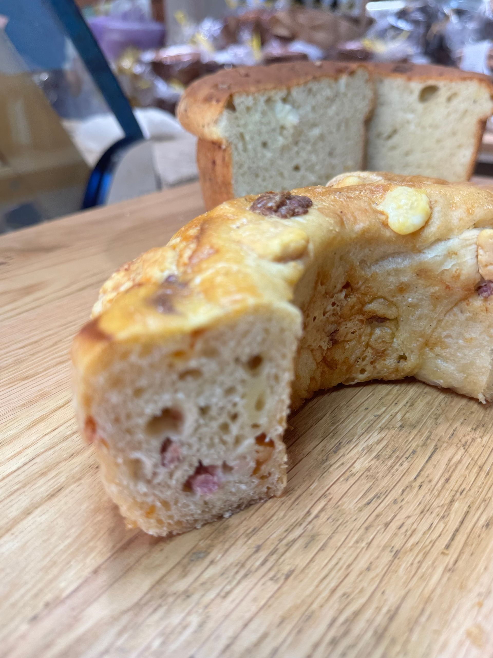 Una fetta di torta con noci su un tagliere di legno, con un'altra fetta sfocata sullo sfondo.