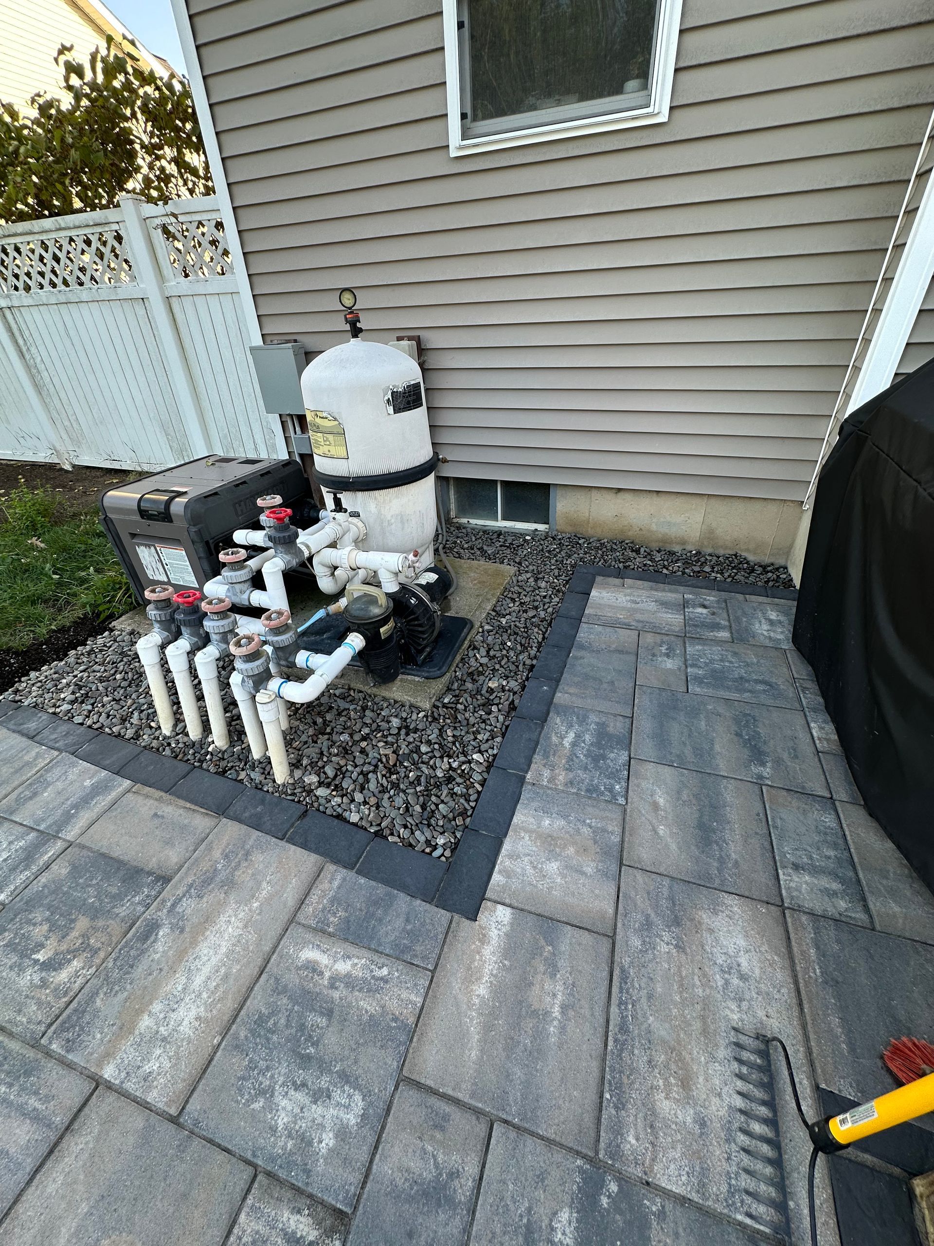 Pool equipment next to a house with a stone patio.