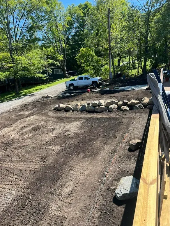 A newly landscaped yard with rocks, a white truck, and a wooden deck railing.