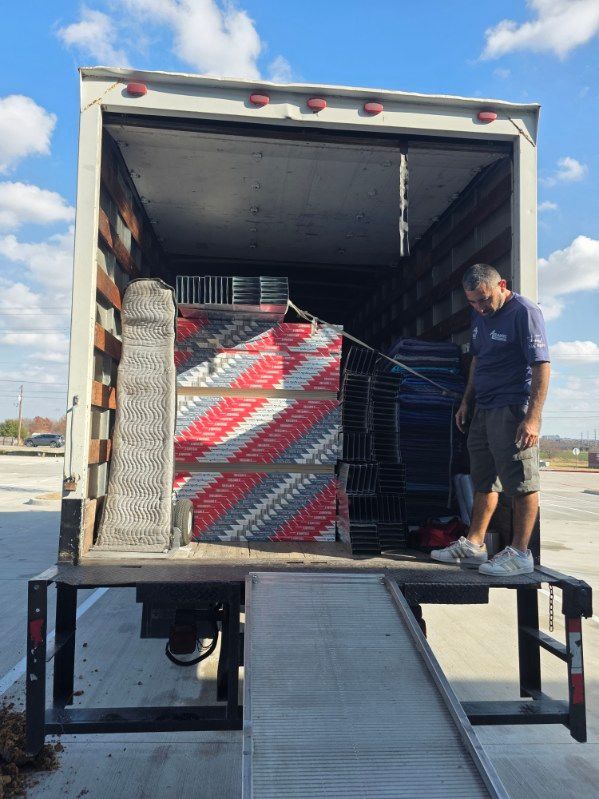 Person in overalls writing on a clipboard beside stacked moving boxes in a bright room