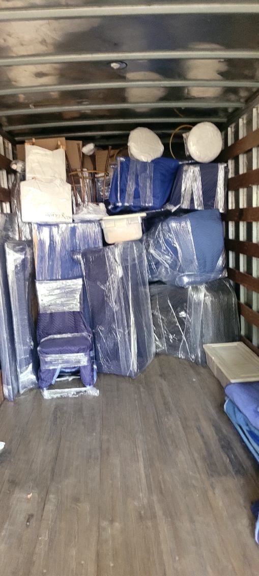 Moving truck loaded with cardboard boxes and furniture parked in a suburban driveway