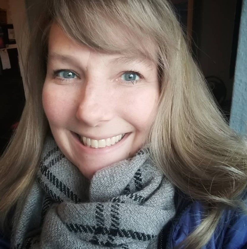 Woman with blonde hair and scarf smiles at the camera.