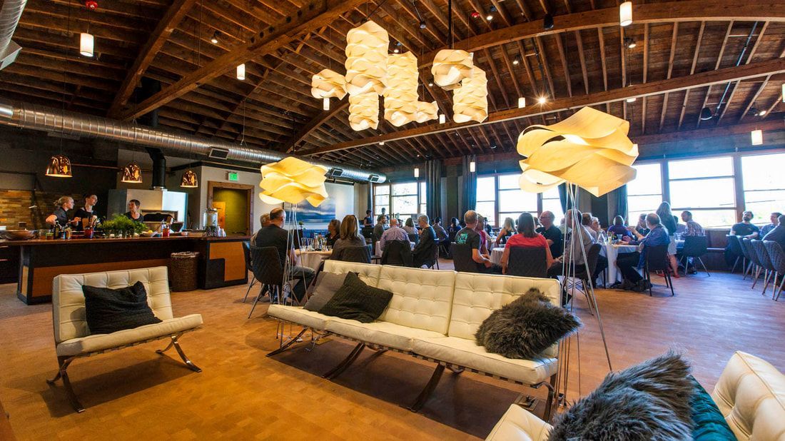 Interior of event space with people seated at tables, couches, and unique light fixtures.