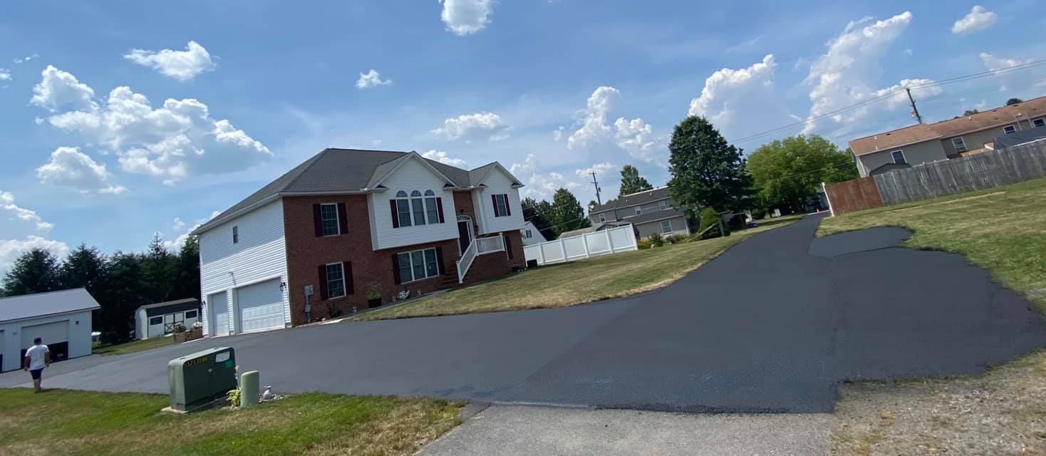 A large house is sitting on the corner of a street next to a paved driveway.