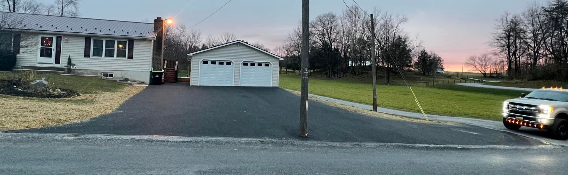 A white truck is parked in front of a house and garage.