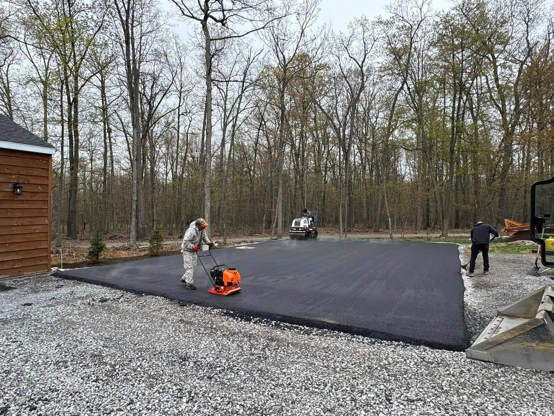 A man is laying asphalt in a driveway.