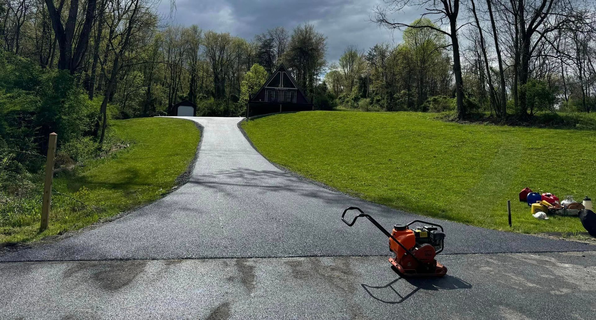 A lawn mower is sitting on the side of a road next to a grassy field.