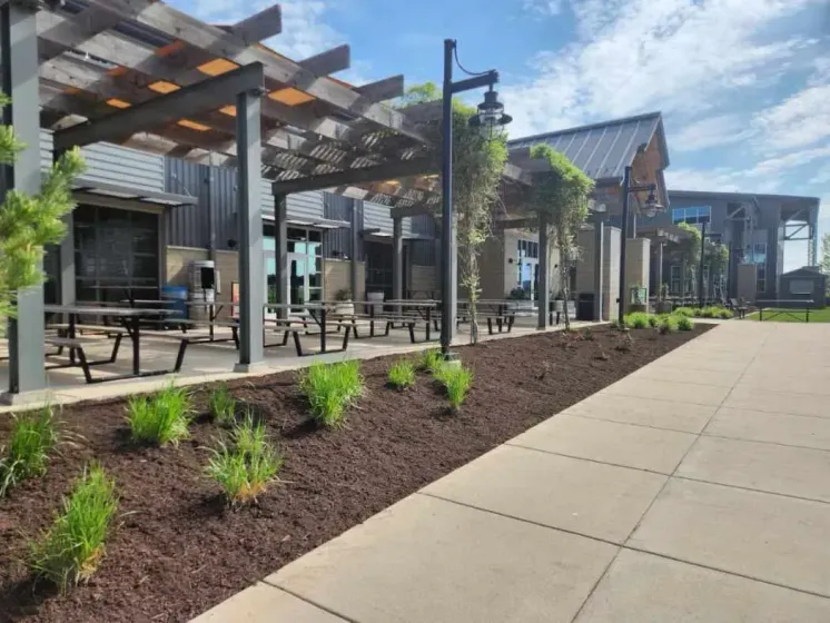 Outdoor restaurant patio with wood pergola, tables, and landscaping.