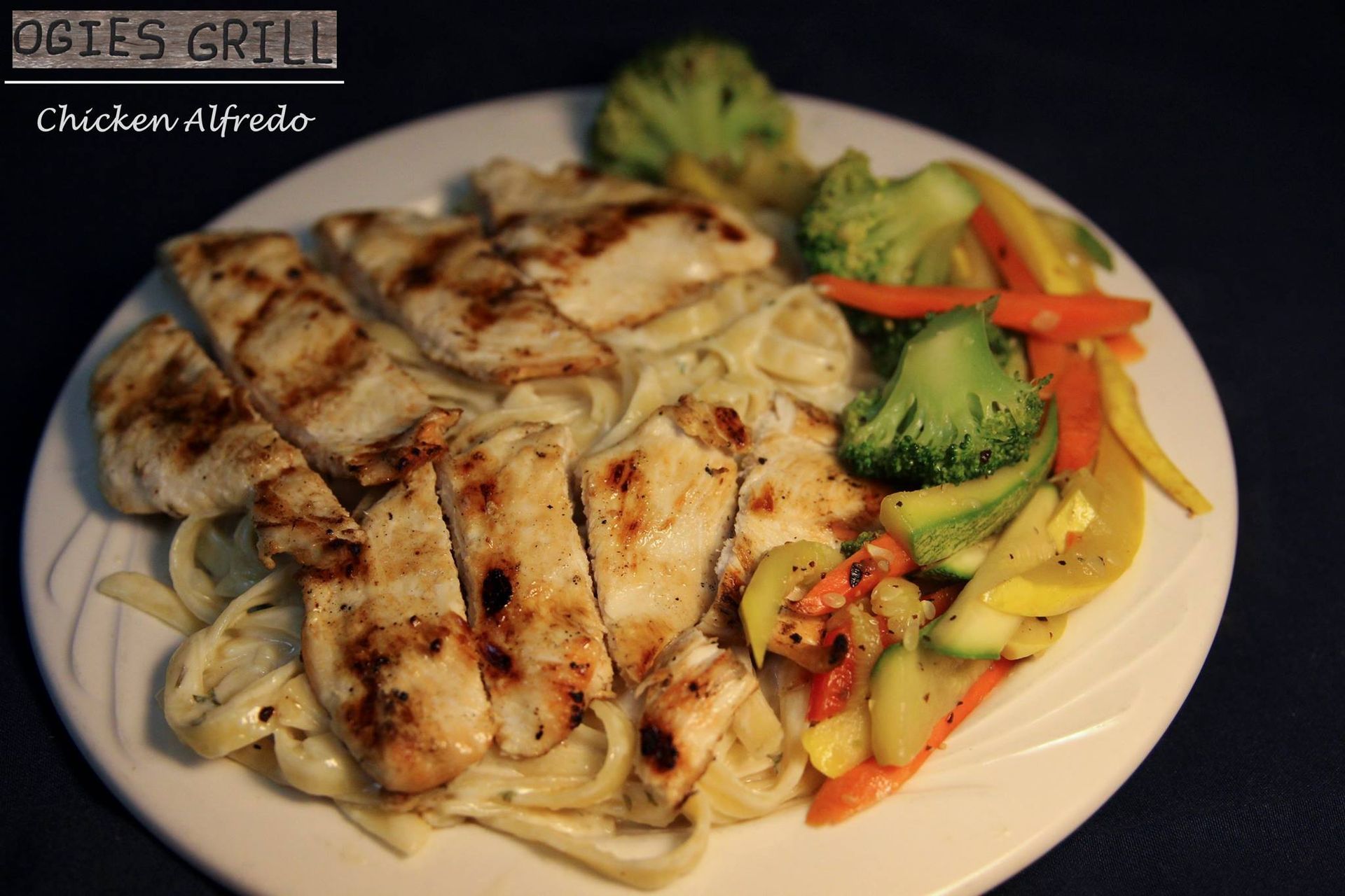 A white plate topped with chicken noodles and vegetables from ogies grill