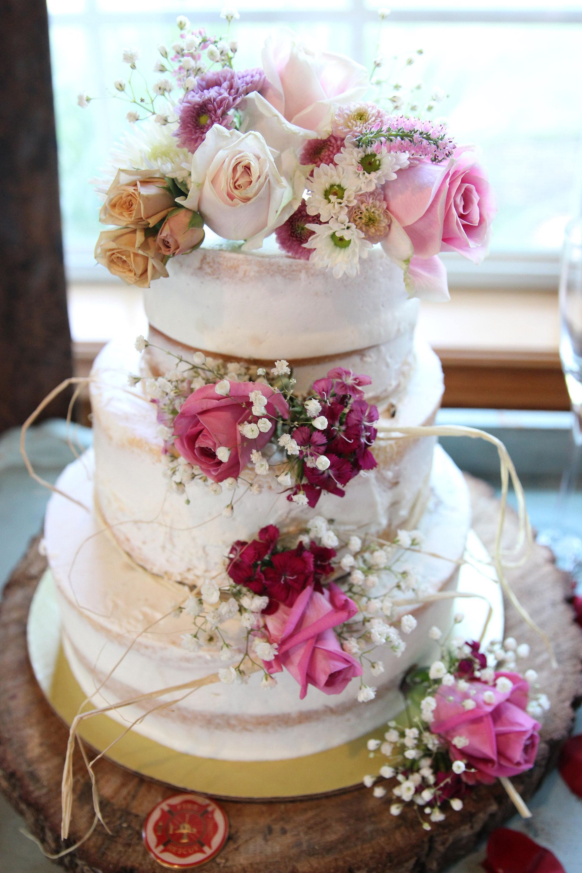 A wedding cake with flowers on top of it is sitting on a wooden table.
