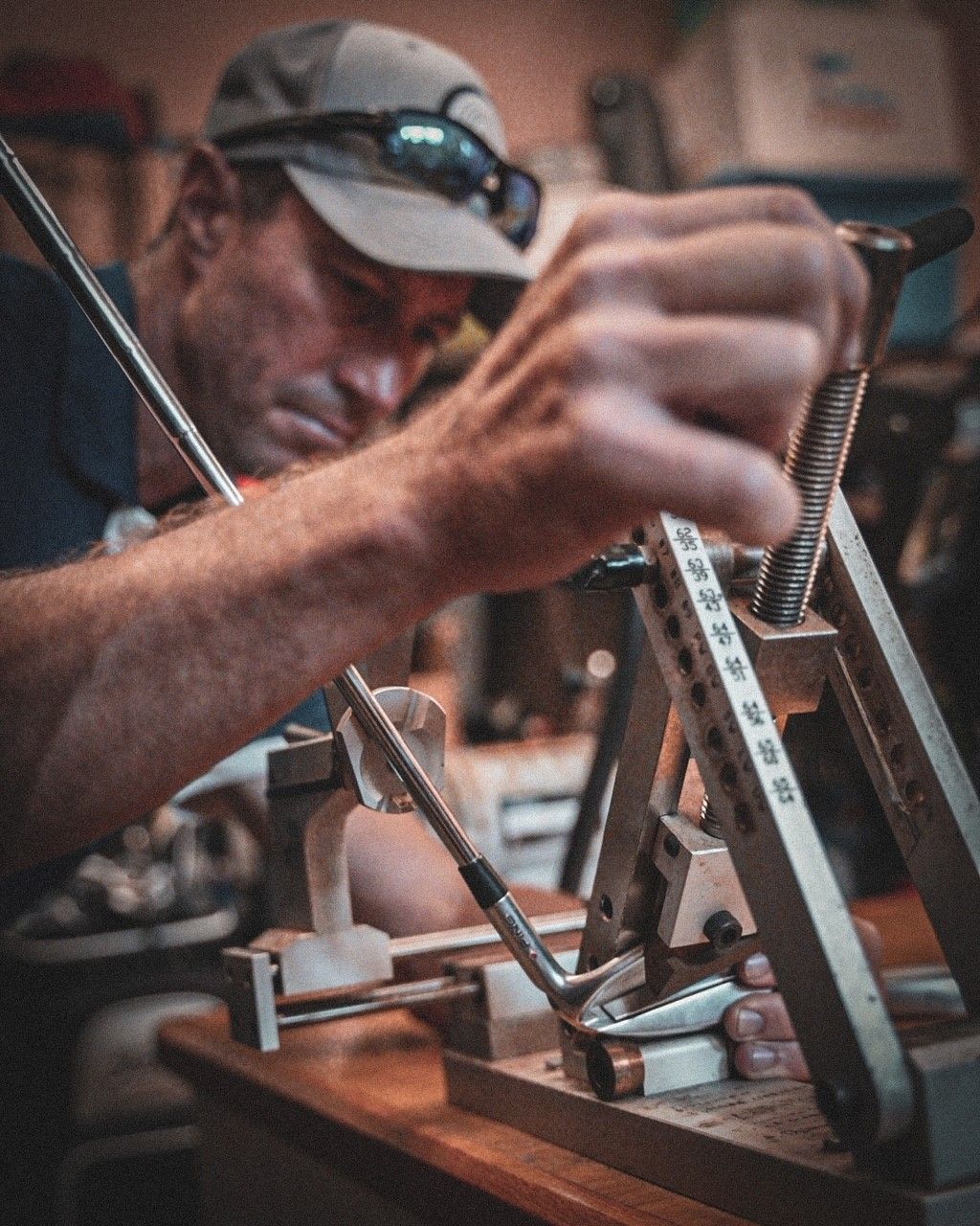 A man is working on a golf club in a workshop.