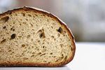 Slice of bread, showing the interior texture with air pockets and a crusty, browned exterior.