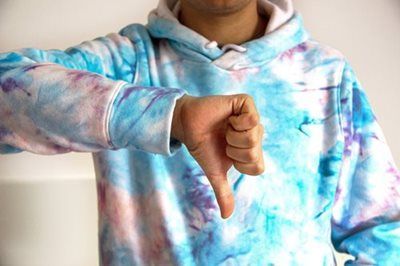 Person in tie-dye hoodie gives a thumbs-down gesture.
