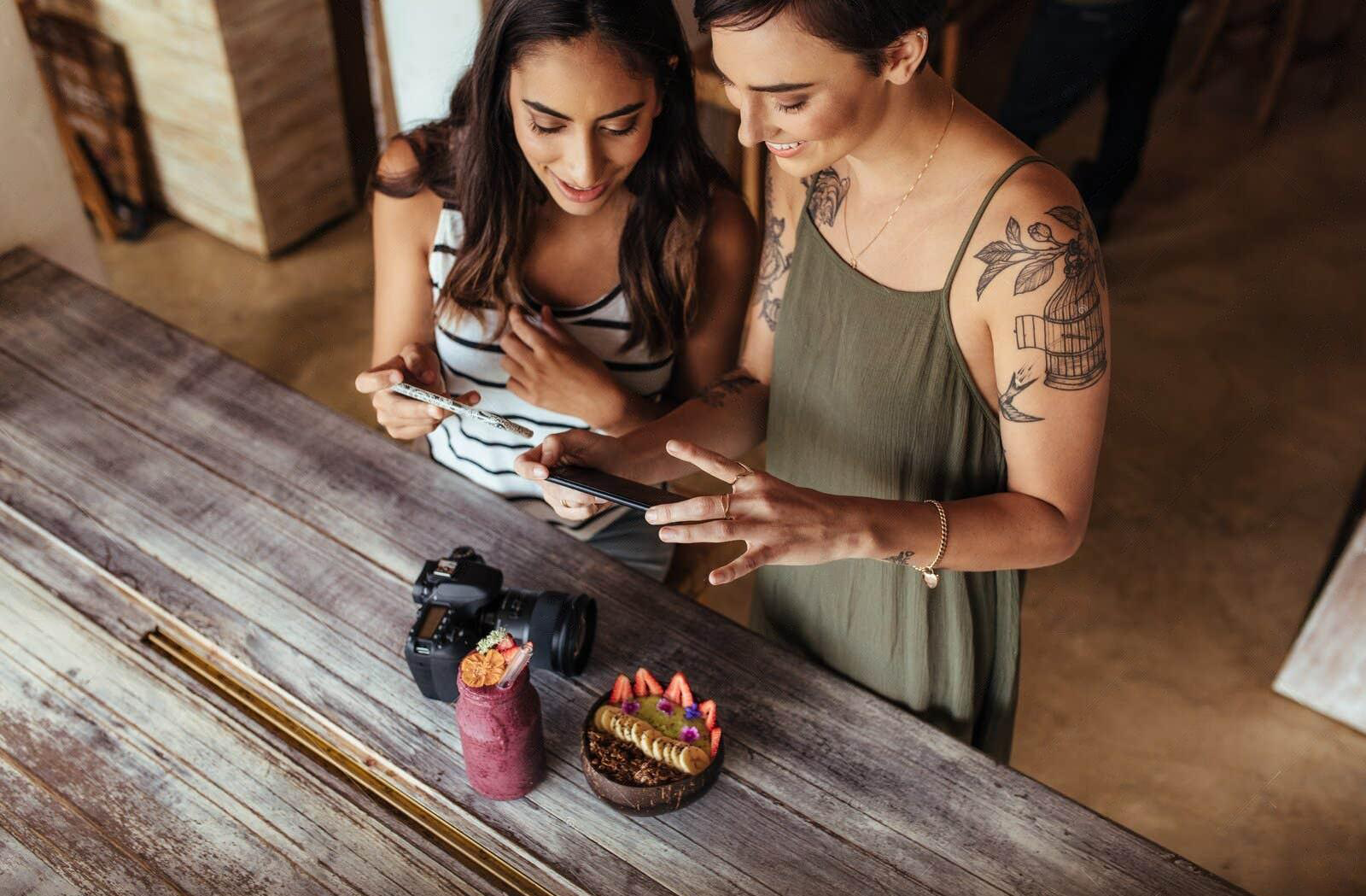 Two women are looking at a cell phone on a table.