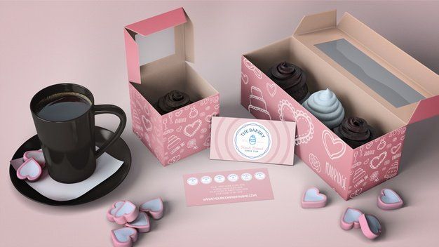 A cup of coffee is sitting on a saucer next to a box of cupcakes.
