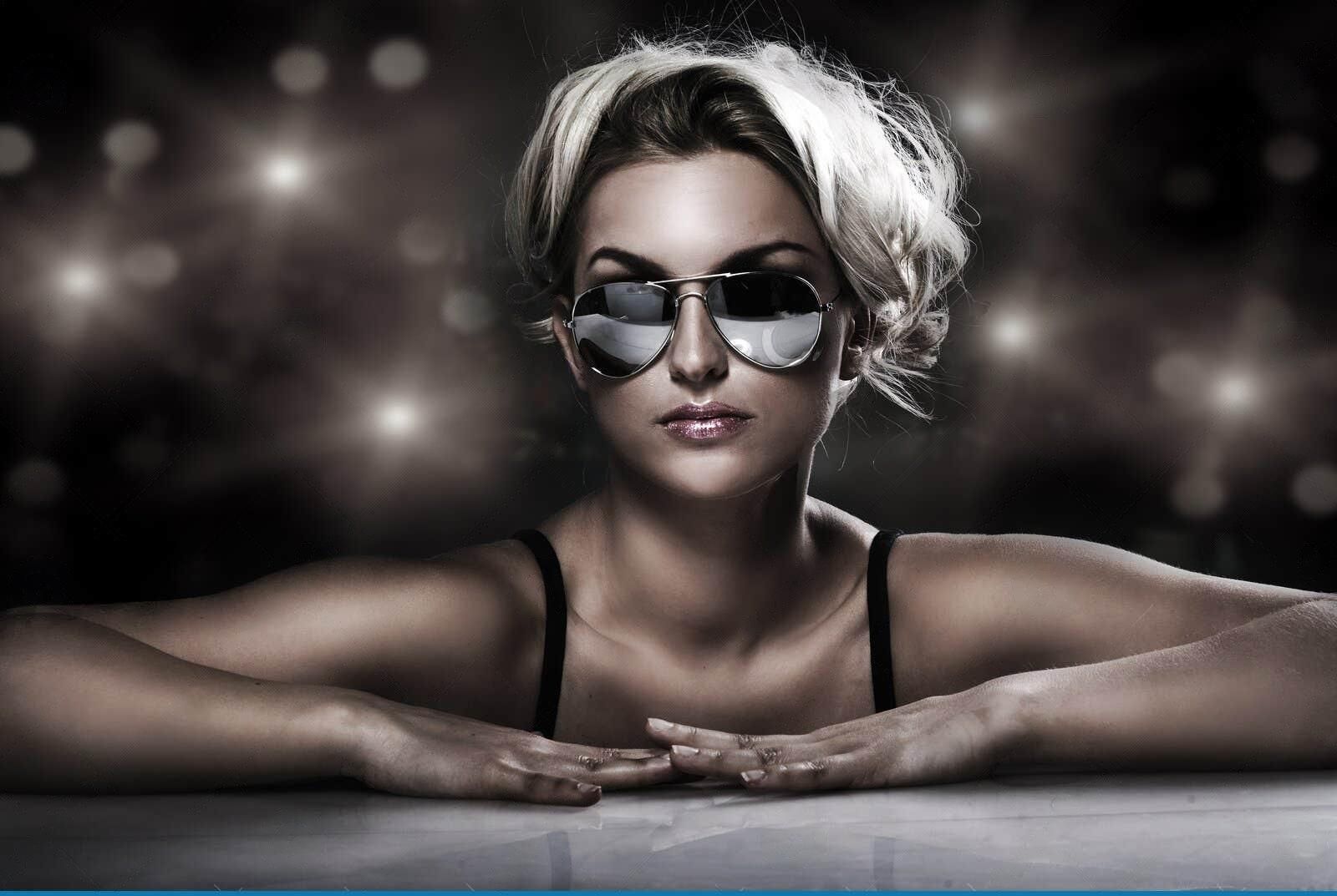 A woman wearing sunglasses is leaning on a table