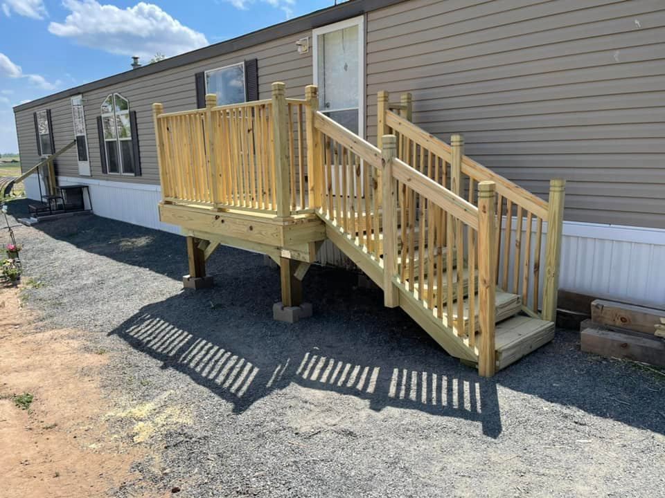 Mobile home with wooden wheelchair ramp and steps on gravel lot