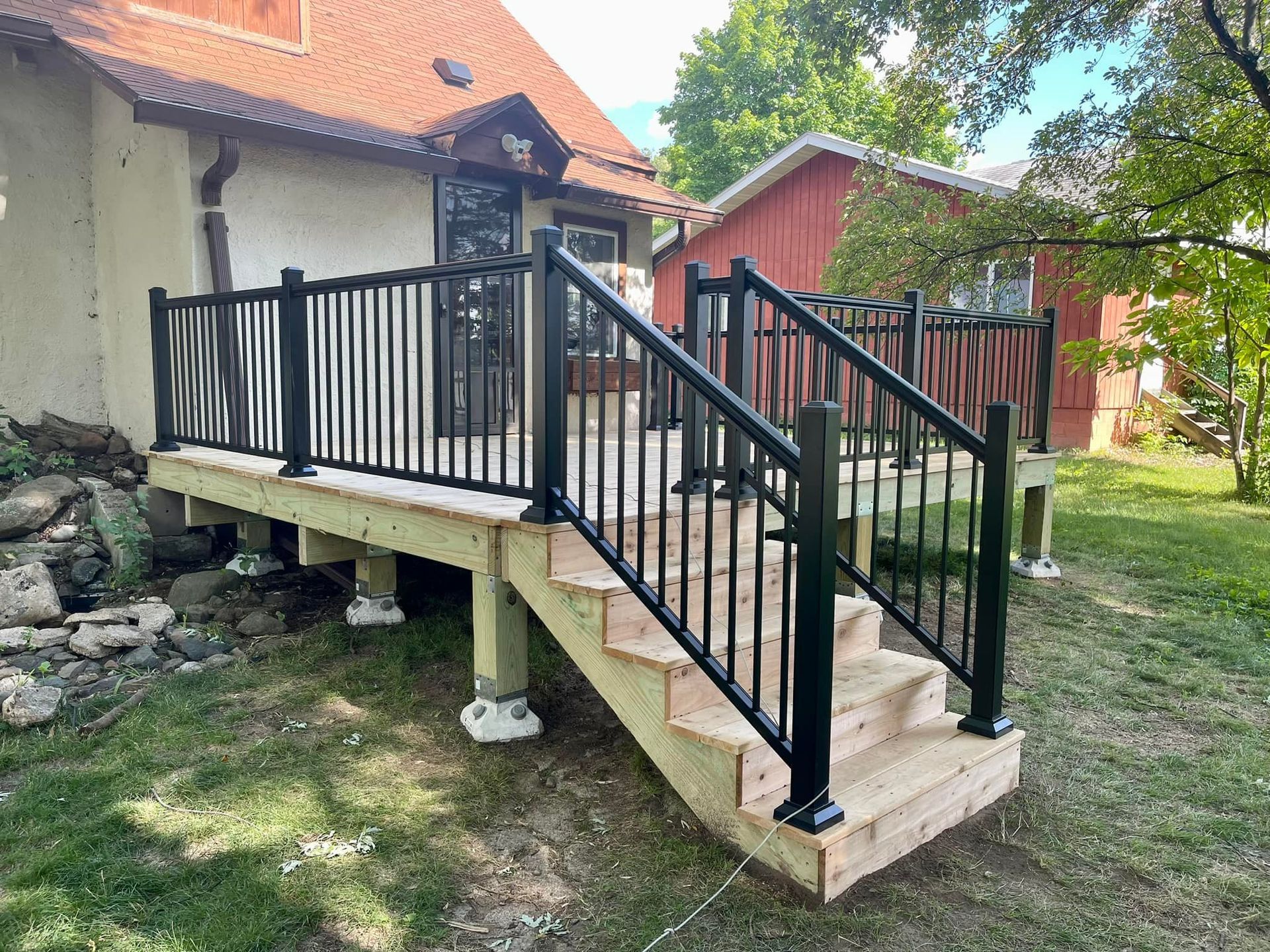 Outdoor ramp with black railings leading to a building entrance beside a red-roofed house