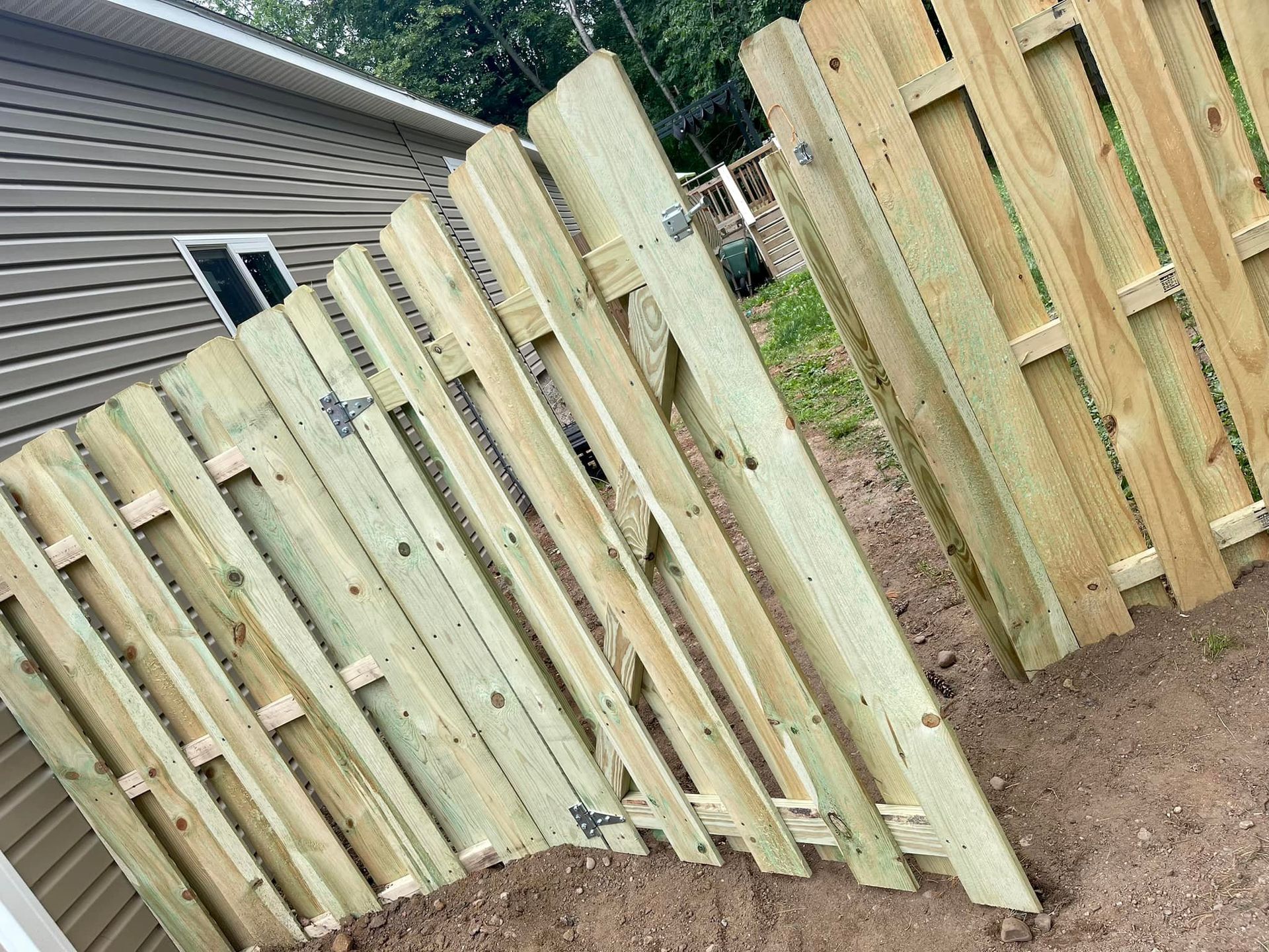 New wooden fence panels along a sloped backyard beside a house