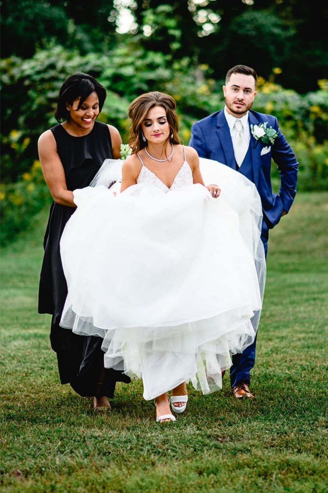 Wedding Planner Charleston WV assisting bride across the grass with wedding gown