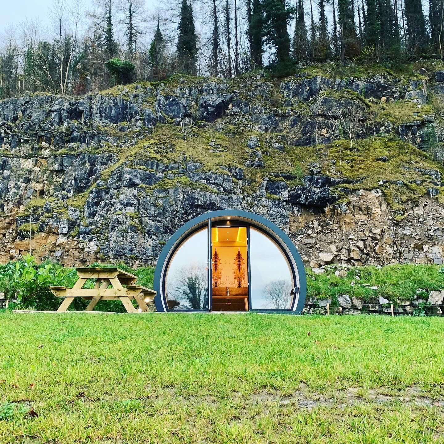 A small house is sitting in the middle of a grassy field.